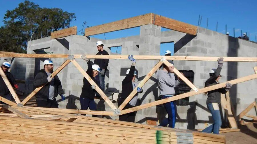 A lot of people working in construction of wooden structure