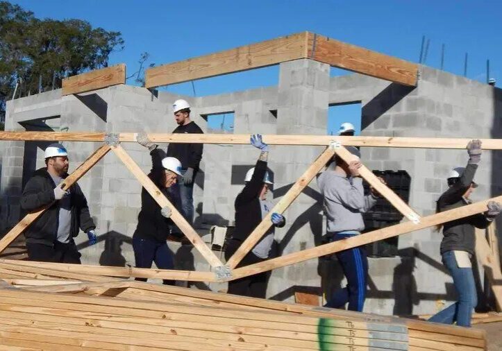 A lot of people working in construction of wooden structure